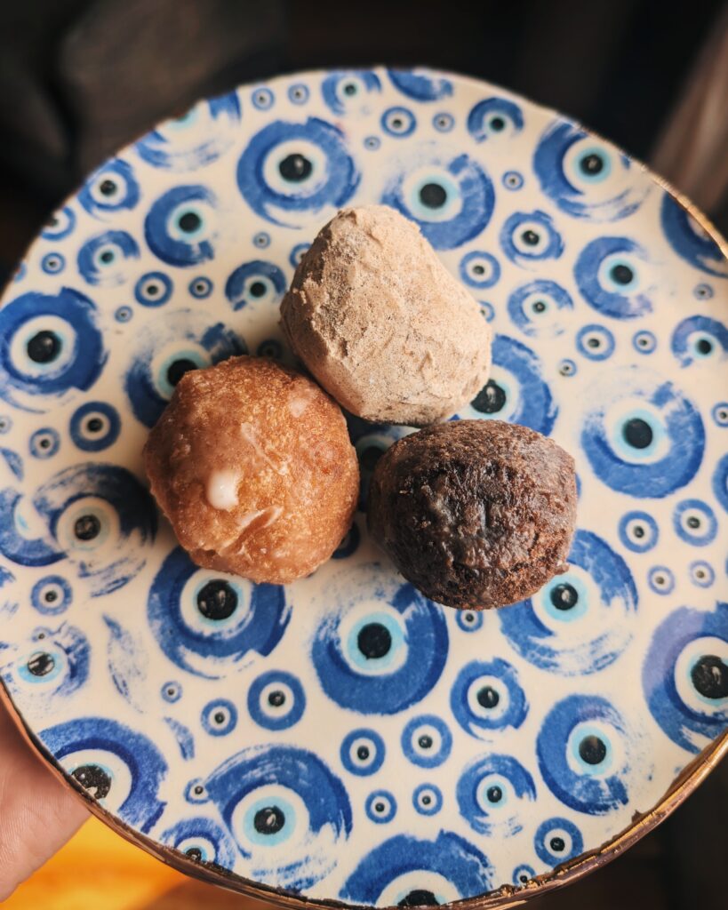 A picture of three donut holes on top of a plate that is decorated with evil eyes.